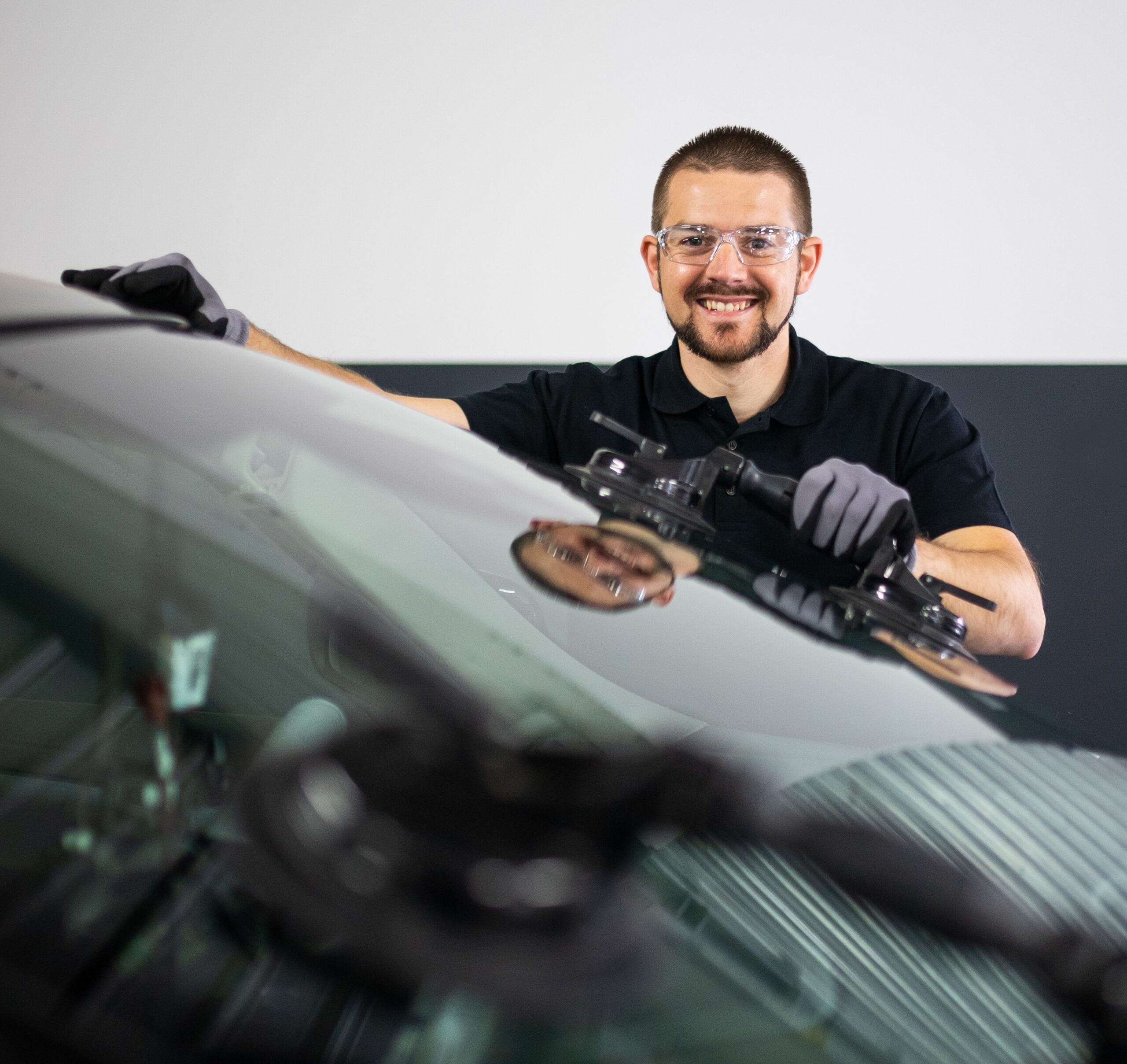 Changement d'un pare-brise a l'aide de ventouse par un technicien souriant 123 Pare-Brise