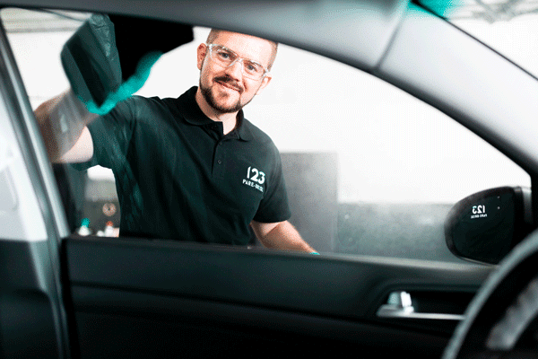 Nettoyage d'une vitre laterale de voiture par un technicien 123 Pare-Brise
