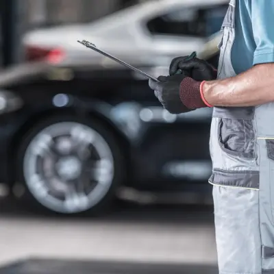 Technicien automobile qui rédige un rapport devant une voiture noire