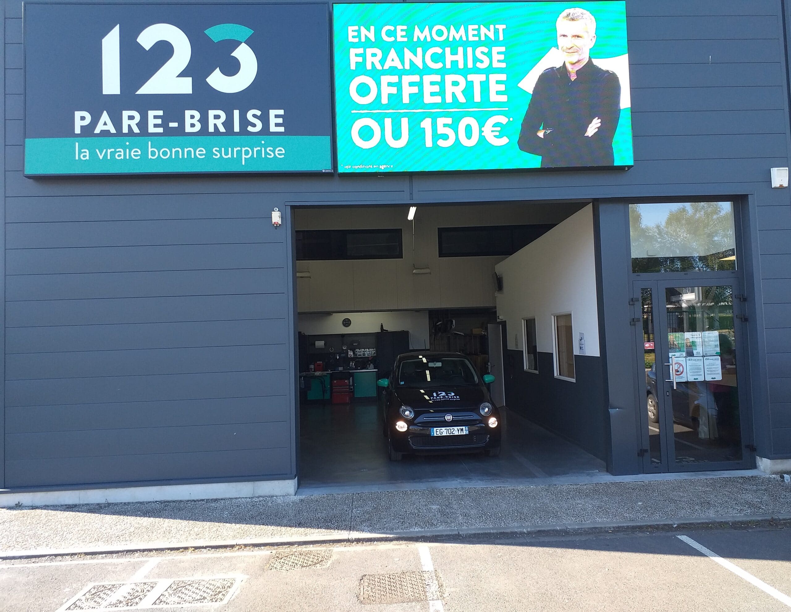 Façade avec un véhicule de prêt floqué 123 Pare-Brise à l'intérieur du garage à Liévin