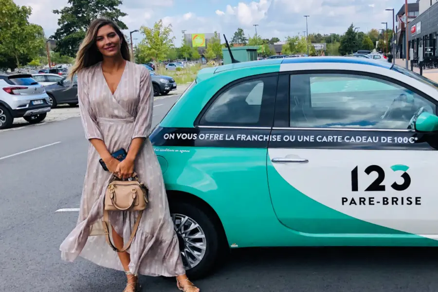 Camille Cerf pose devant un véhicule de prêt 123 Pare-Brise.