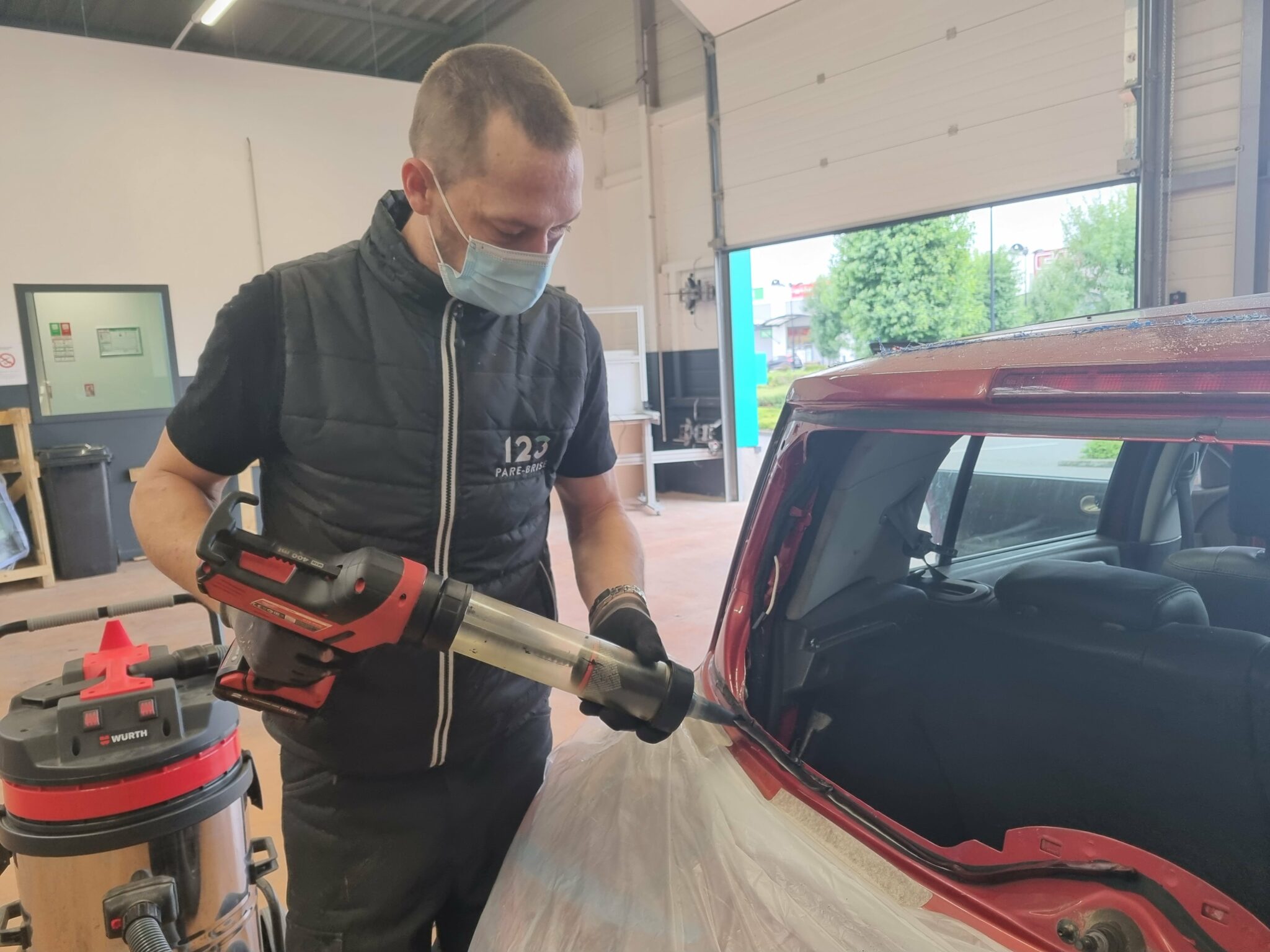 Pose de la colle lors d'un remplacement de lunette arrière dans le garage 123 Pare-Brise Dreux